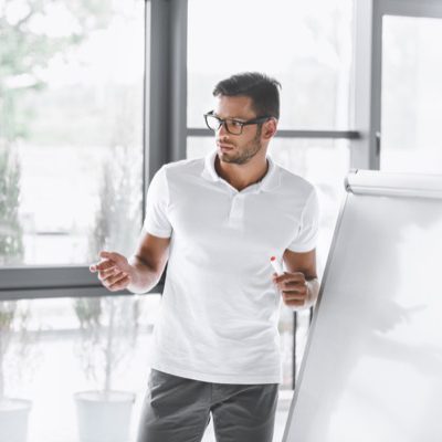 concentrated businessman making presentation at white board in office